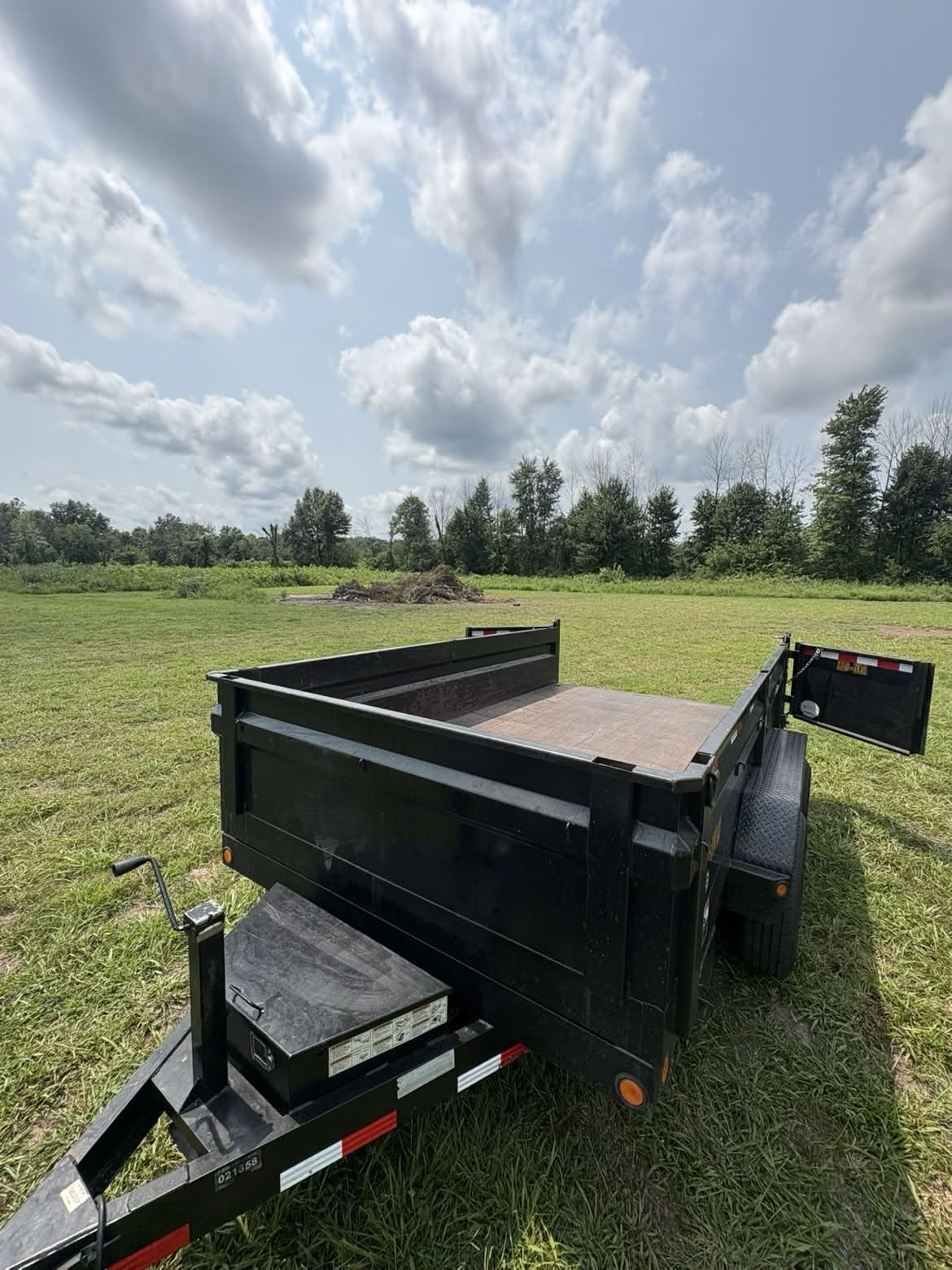 Morgan's Tree dump trailer with the tailgate open, brush pile behind it